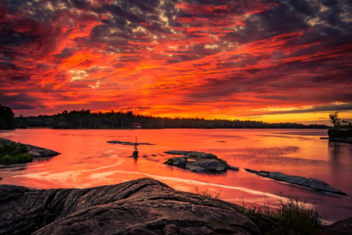 Coucher de soleil rougeoyant sur un lac bordé de rochers